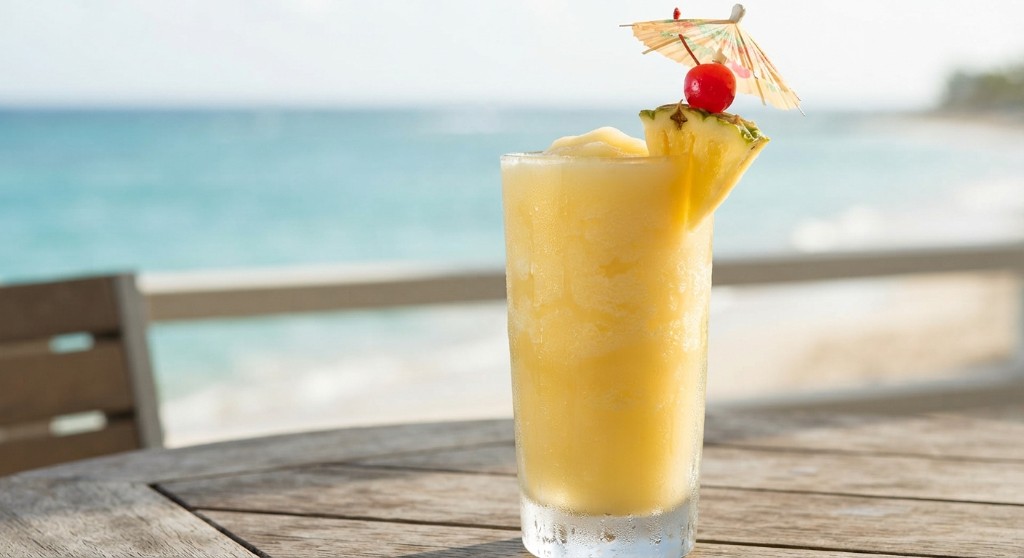 Piña colada with pineapple and cherry on a beach table